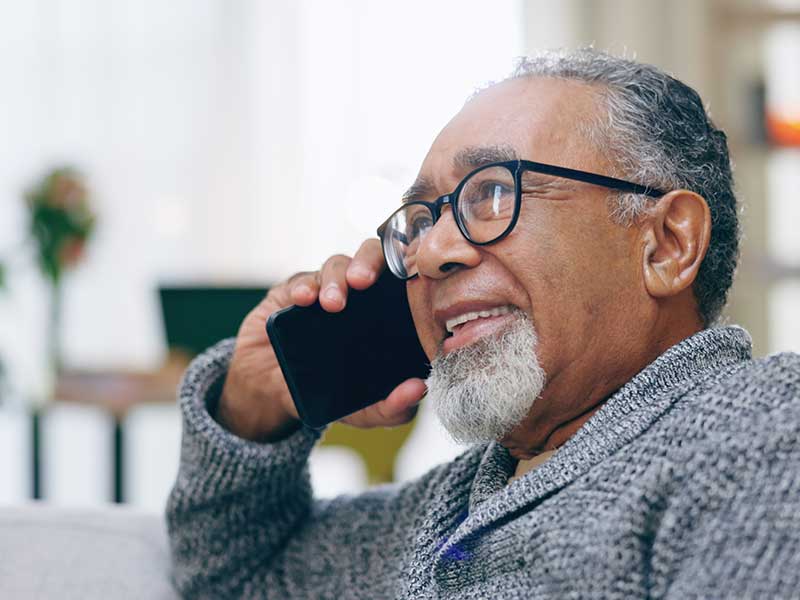 Carribean man with white beard on phone